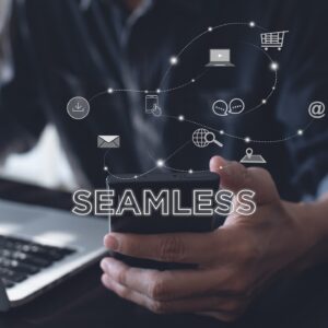 Hände halten ein Smartphone mit dem Schriftzug „SEAMLESS“. Digitale Icons für Shopping, E-Mail, Video und Social Media schweben verbunden über dem Gerät.